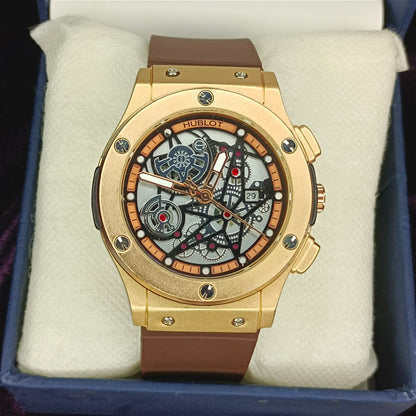 Bronze chronograph watch with brown strap on a white cushion inside a blue box